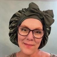 Person wearing glasses and a dark green headwrap.