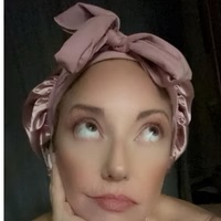 Person with a pink headscarf looking upwards with a thoughtful expression.