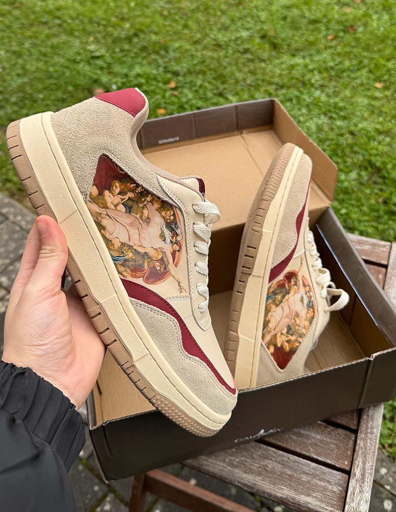 Art-themed sneakers with vibrant design in a shoebox outdoors.