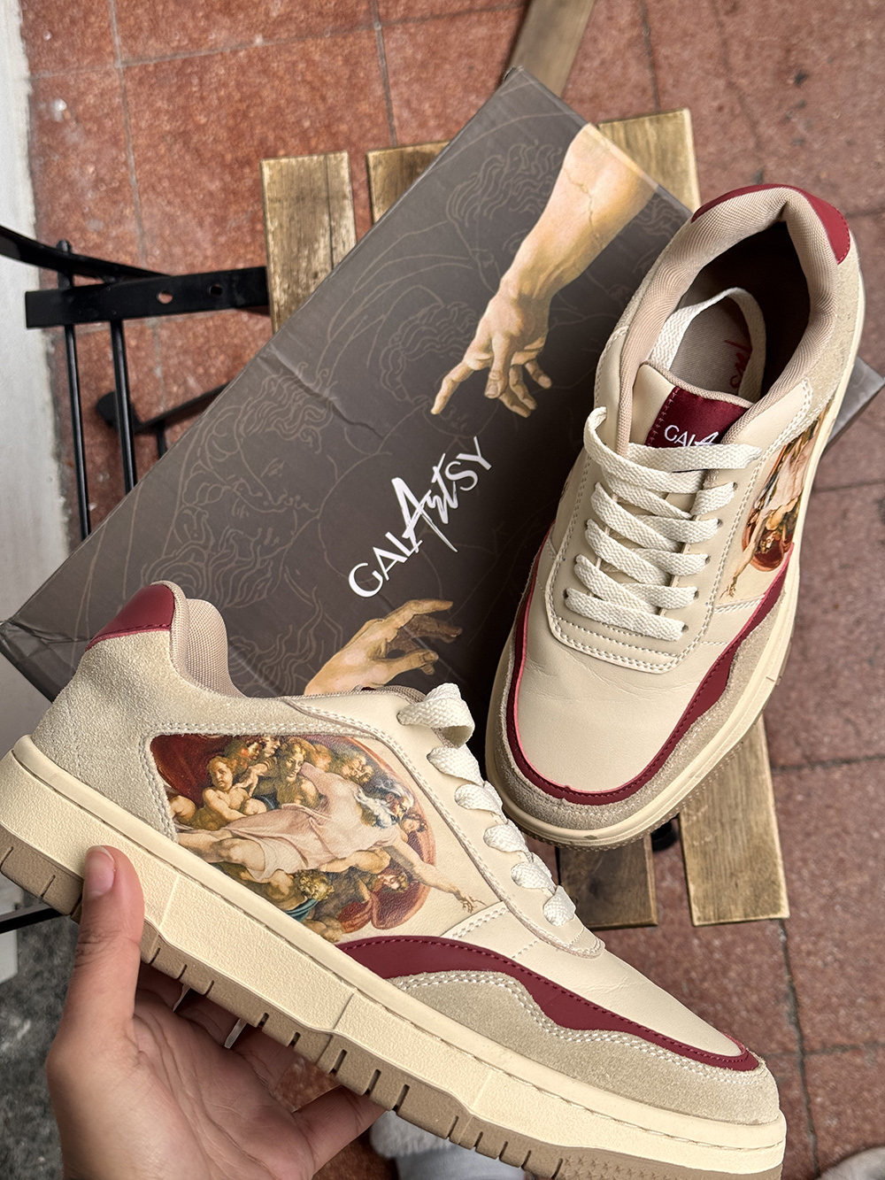 Sneakers with artistic design featuring a classical painting detail, alongside matching themed shoebox.
