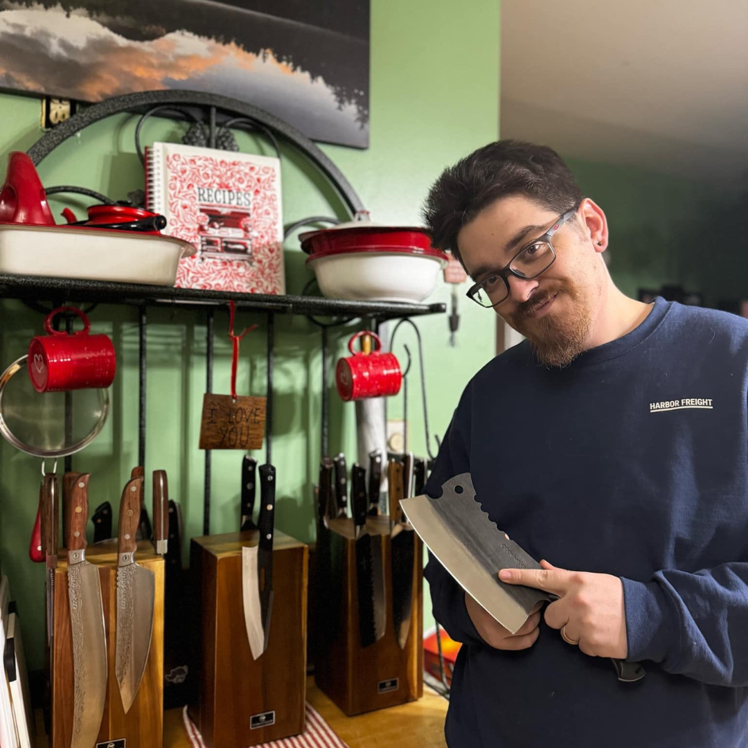Person holding a large knife in a kitchen with knife blocks and cookware.