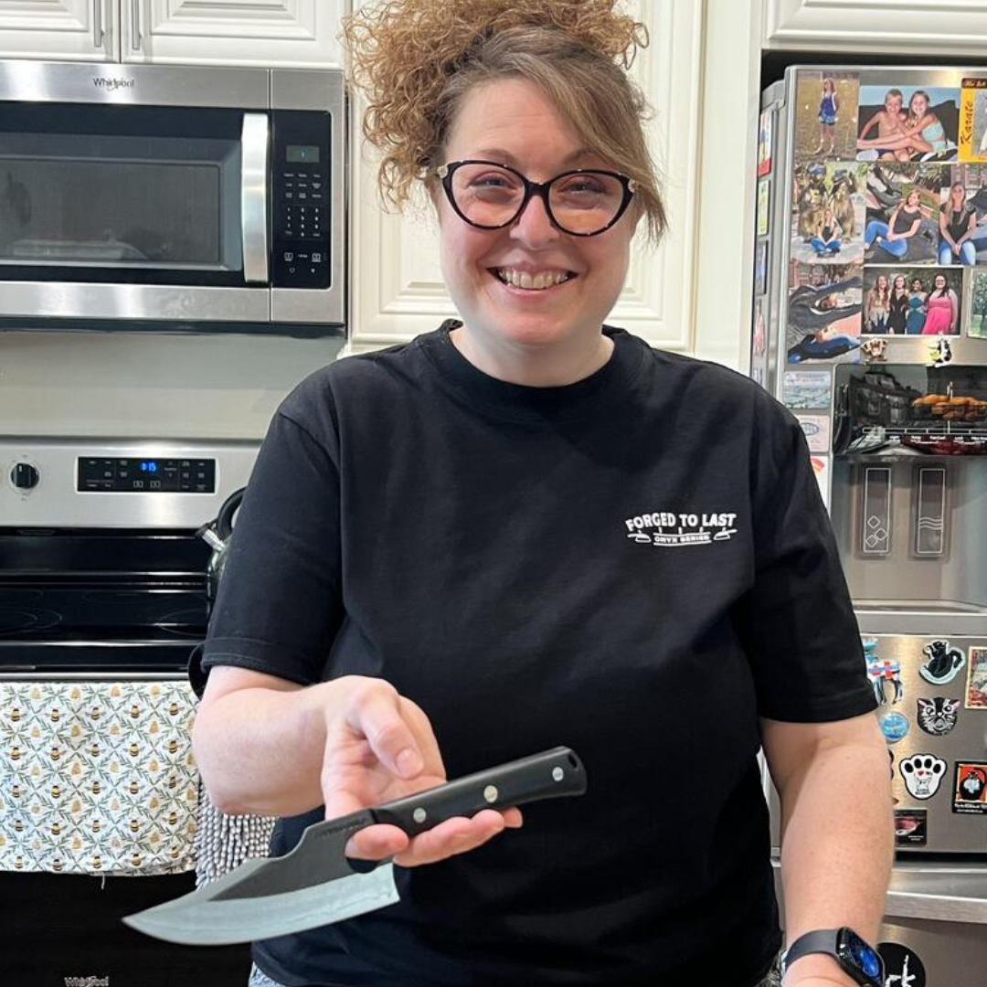 Smiling person holding a knife in a kitchen setting.