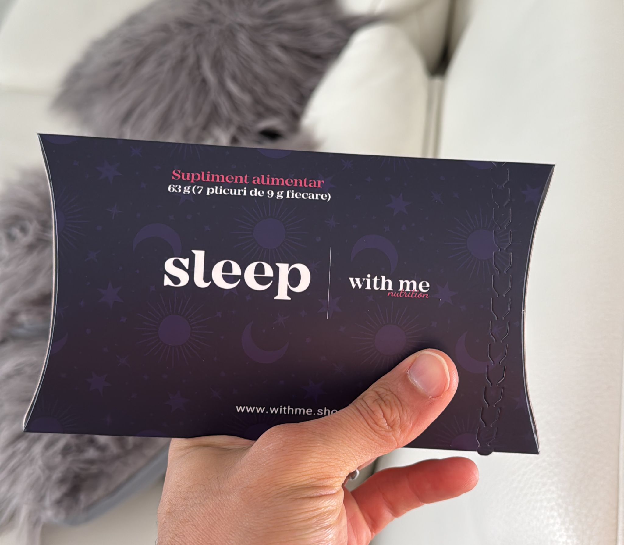 Hand holding a dark package labeled 'sleep with me nutrition' with celestial designs.