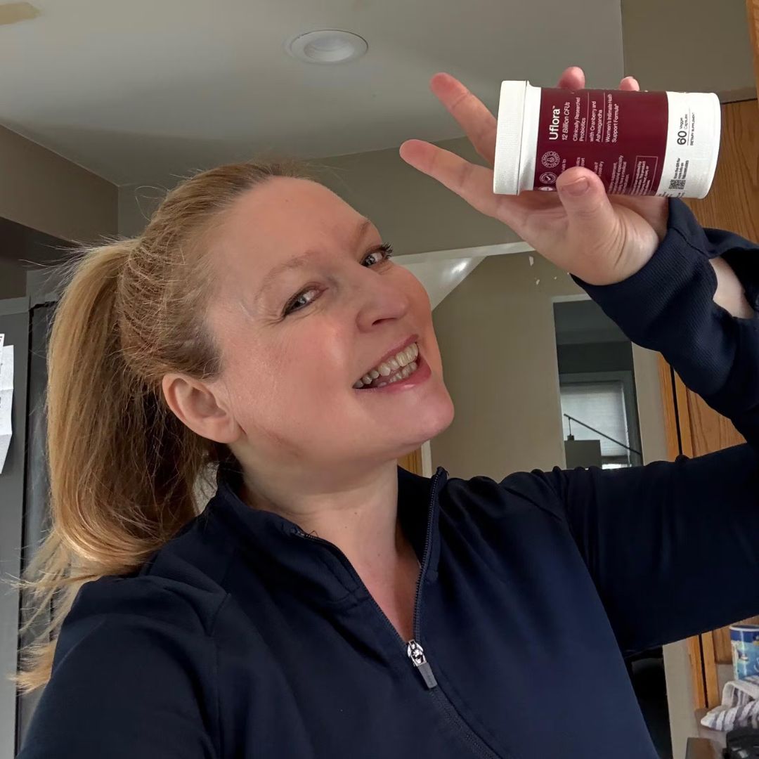 Person smiling, holding a small container in a kitchen.