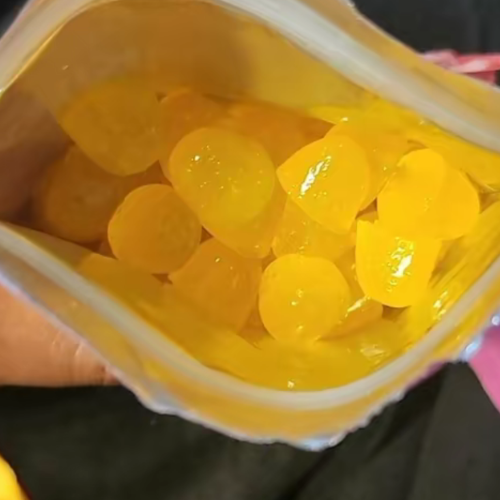A close-up view inside an open bag filled with yellow, shiny gummy candies.