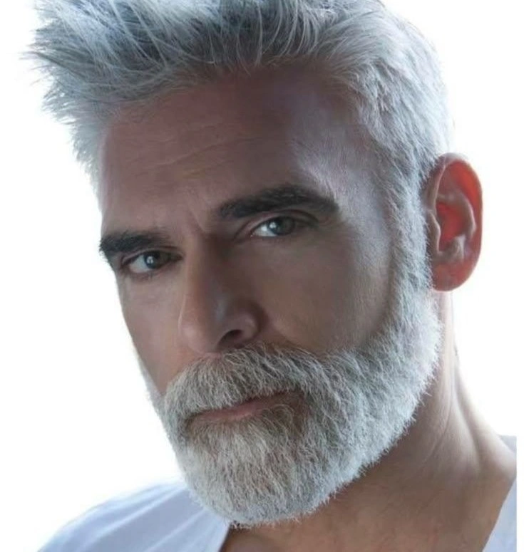 Man with white hair and beard, wearing a white shirt.