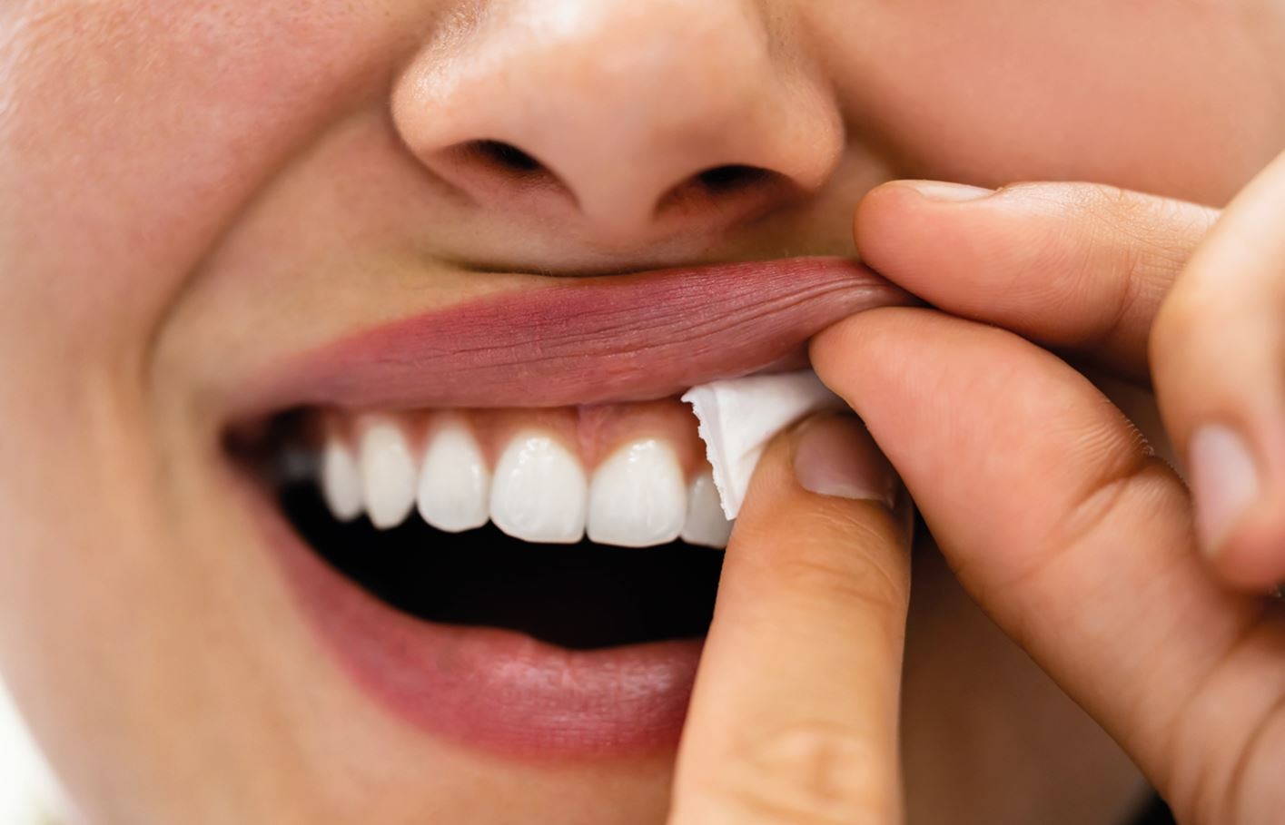 Close-up of a person cleaning teeth with a tissue.