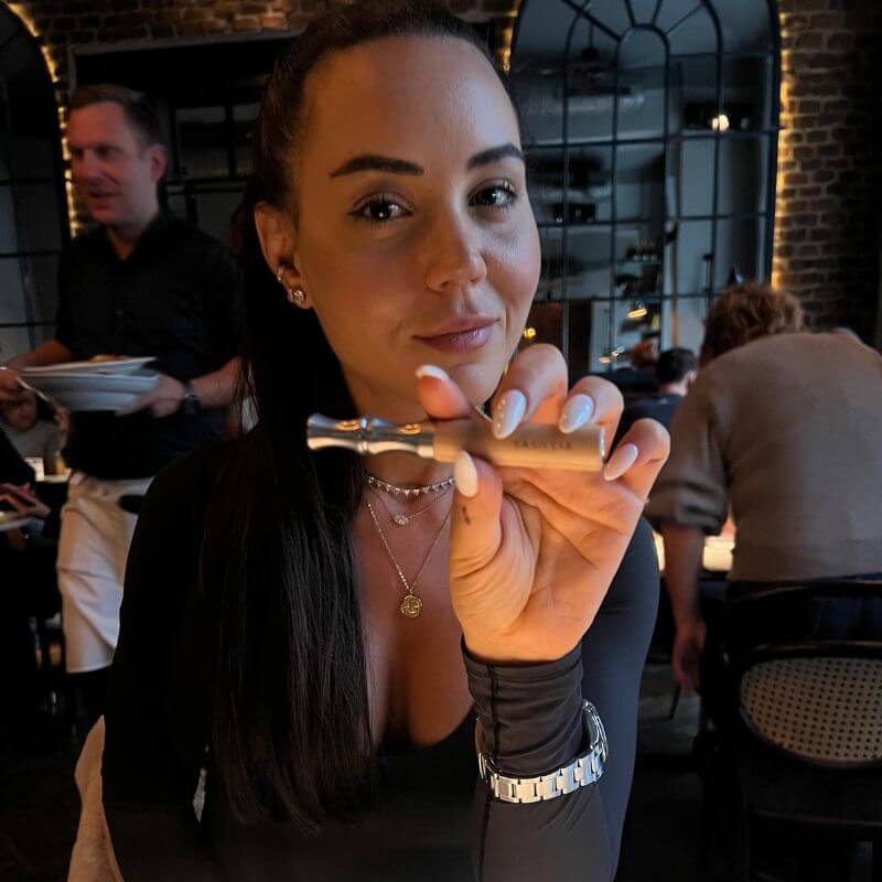 Person holding a small metallic item in a dimly lit restaurant.