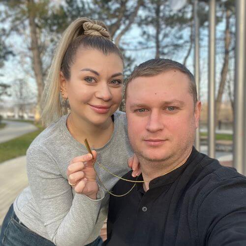 A couple posing outdoors with trees in the background.