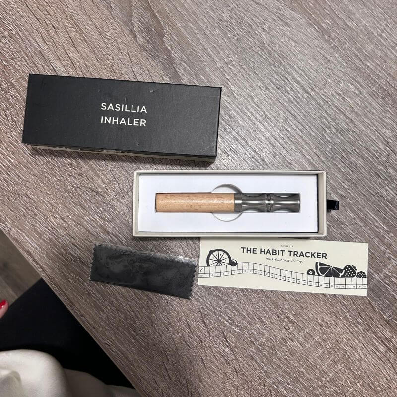An inhaler, box, and habit tracker on a wooden table.