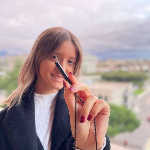Person holding a pen with a blurred cityscape background.