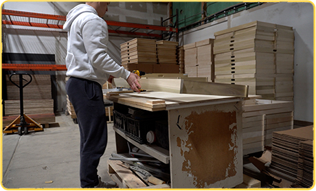 Person working in a warehouse with wooden panels and pallets.