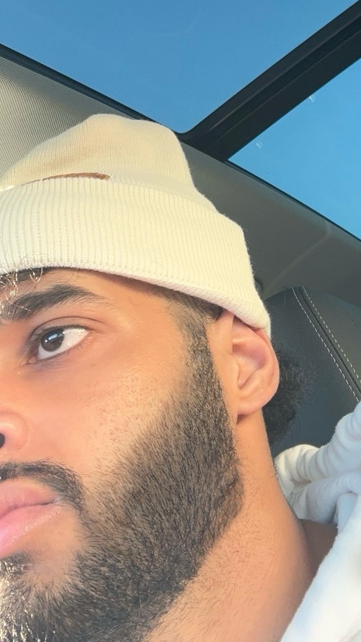 Close-up of a bearded person wearing a cream beanie in a car.