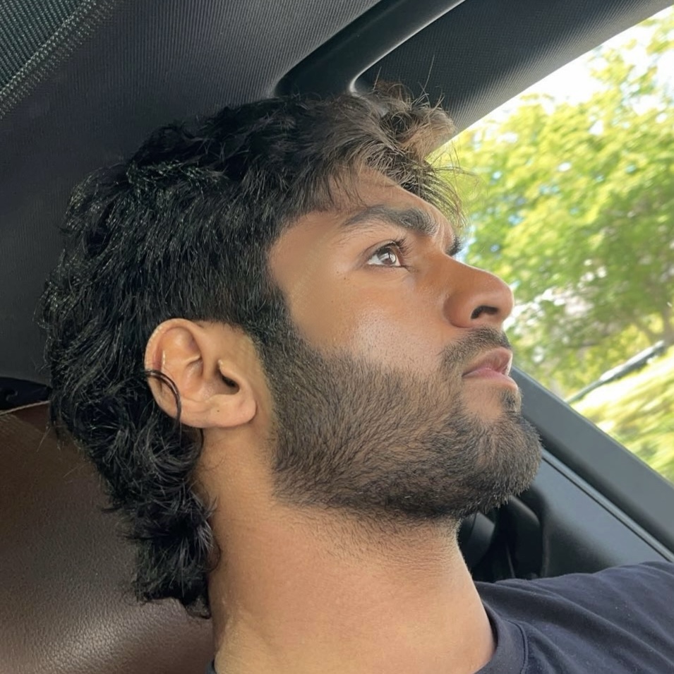 Man with beard sitting in a car, looking outside.