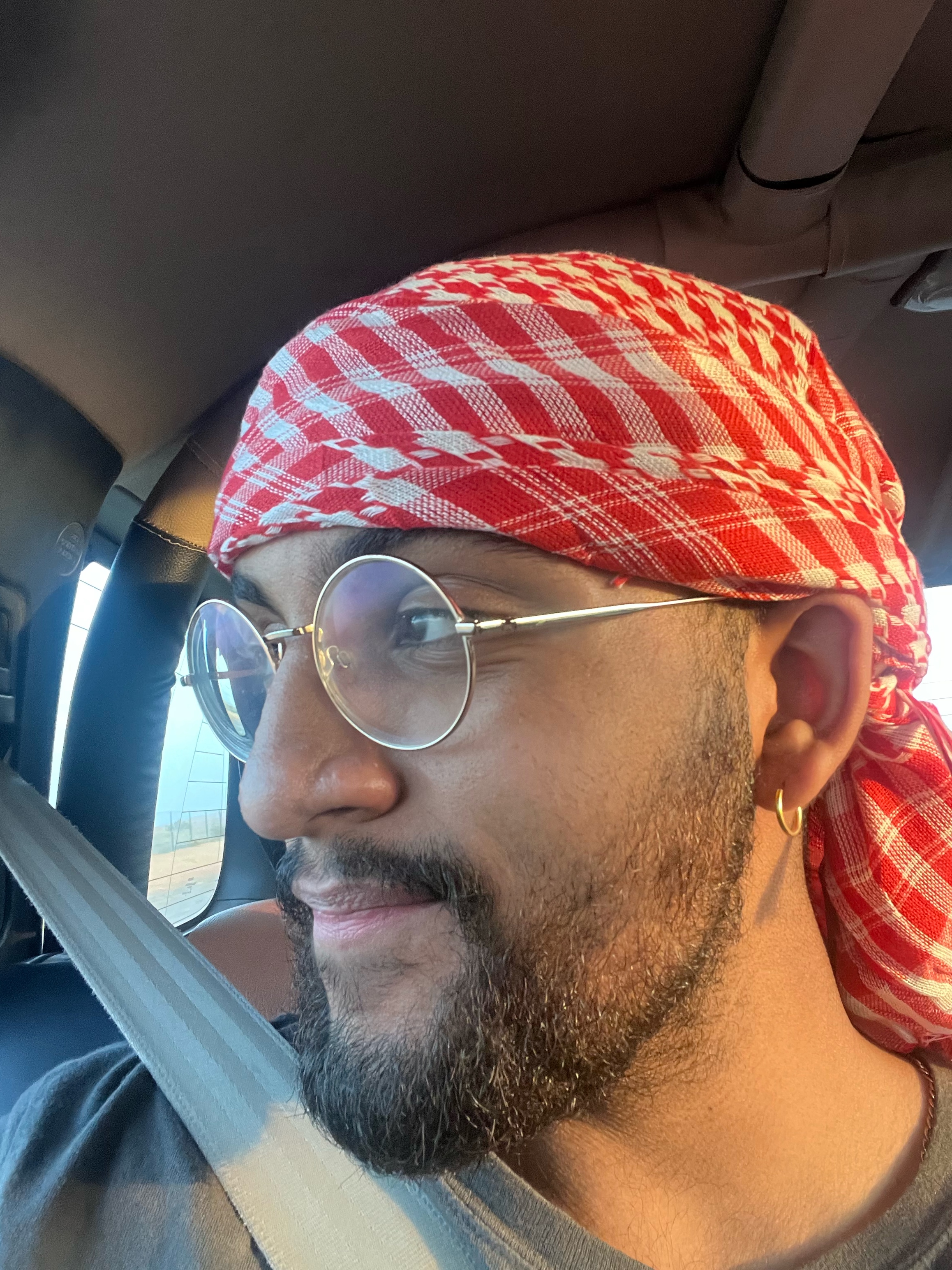 Person wearing a red headscarf and glasses, inside a car.