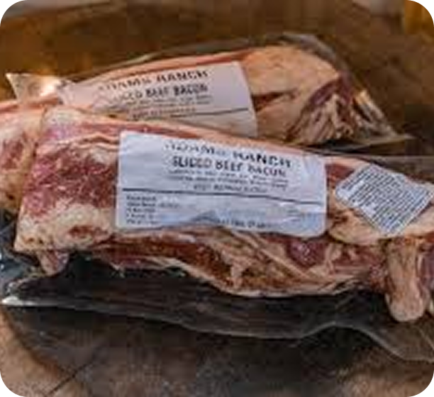 Vacuum-sealed packages of sliced beef bacon on a wooden surface.