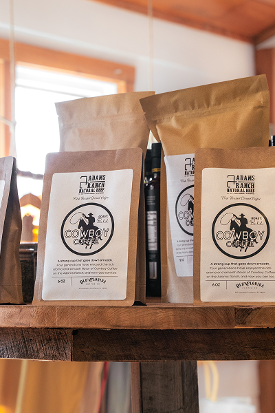 Bags of Cowboy Coffee with logo on wooden table.