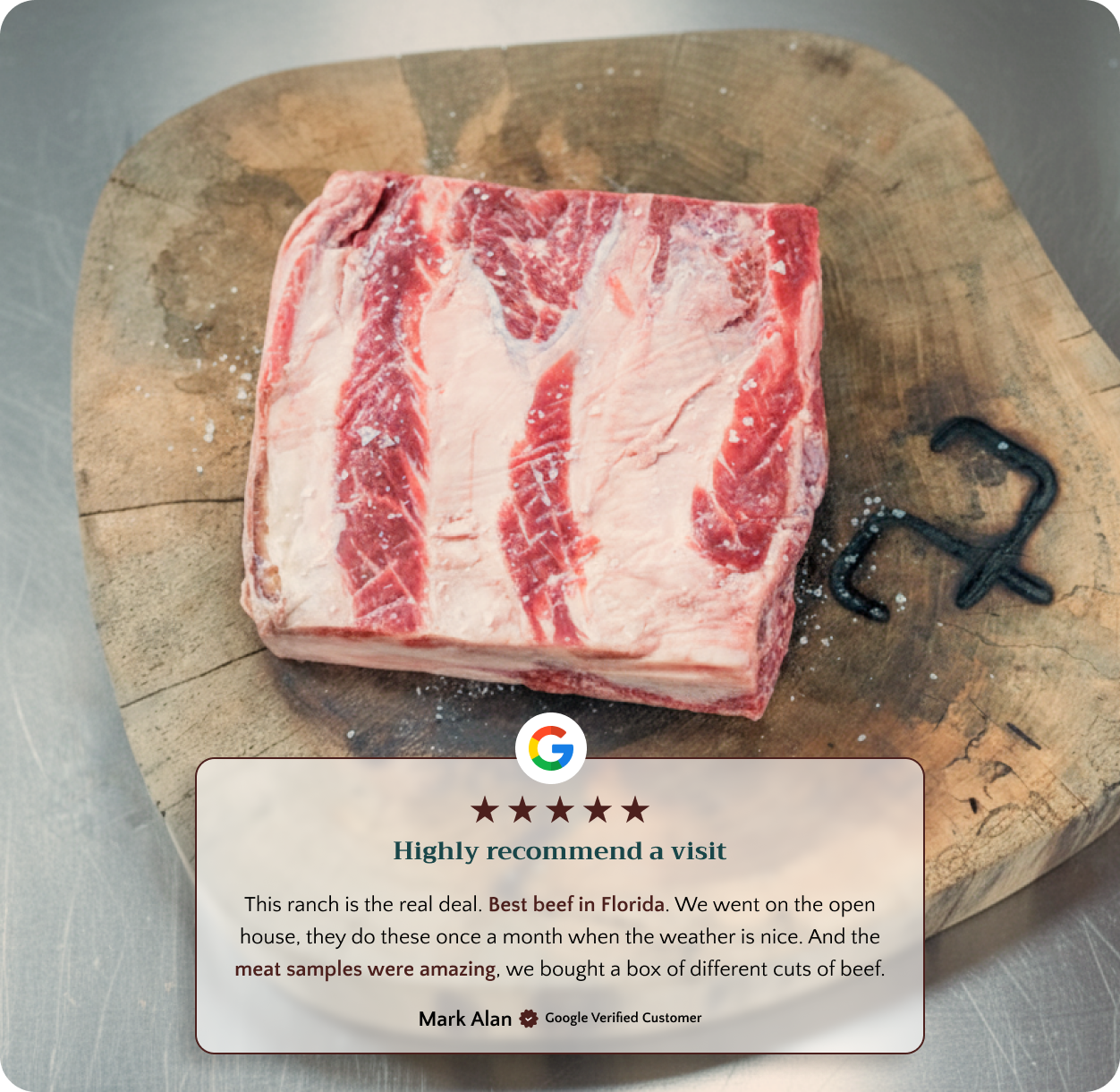 A raw beef cut on a wooden board with a branding iron and salt nearby.