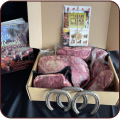 Box containing packaged cuts of raw meat and a booklet.