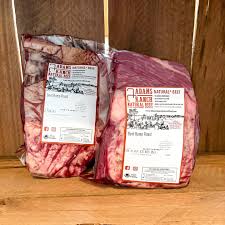 Two packages of raw beef with visible labels on a wooden surface.