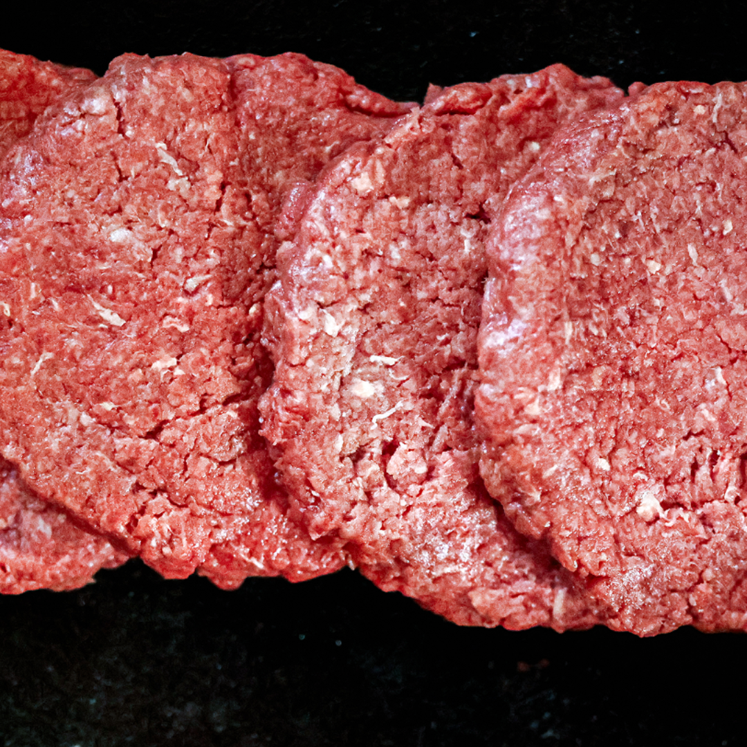 Close-up of raw hamburger patties on a black surface.