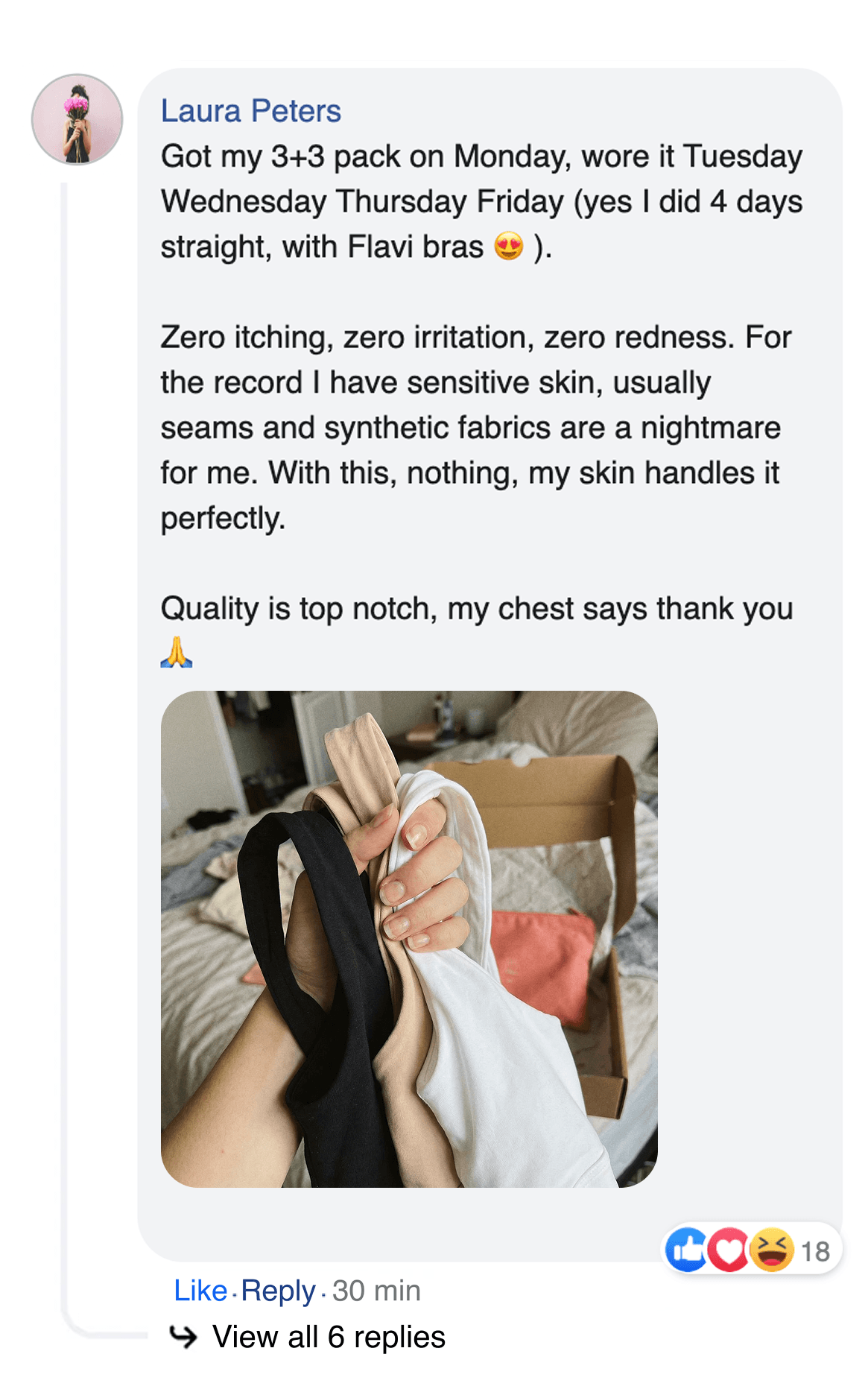 A person's hand holding three bras in black, beige, and white over a cardboard box.
