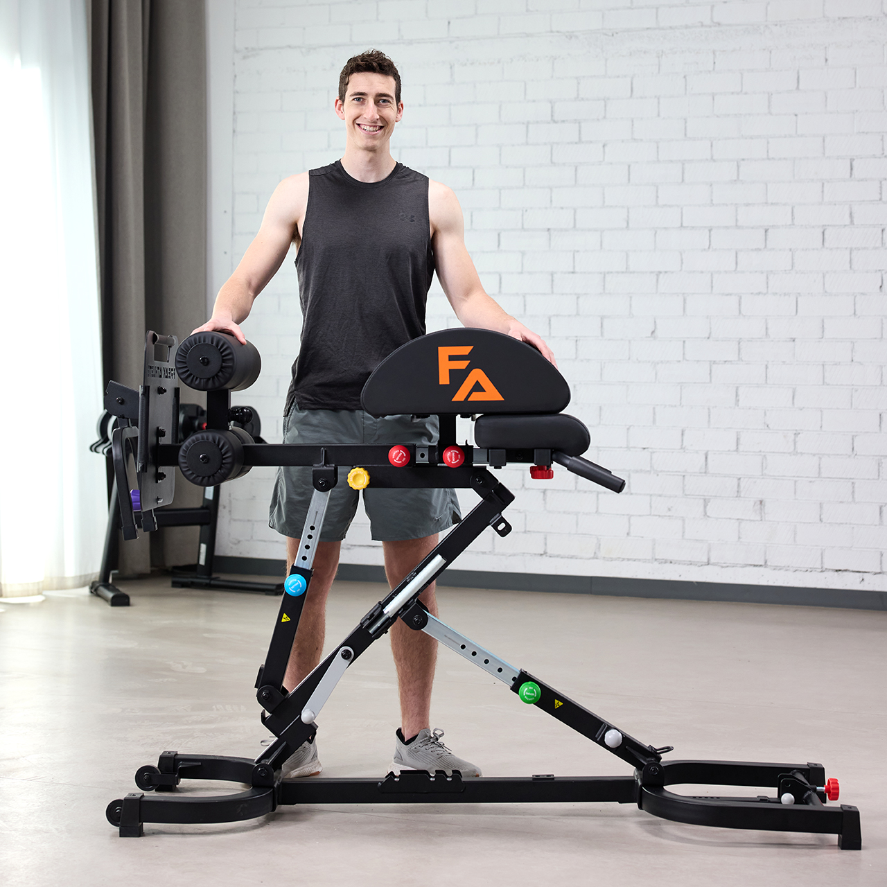 Man standing beside a fitness machine in a gym setting.