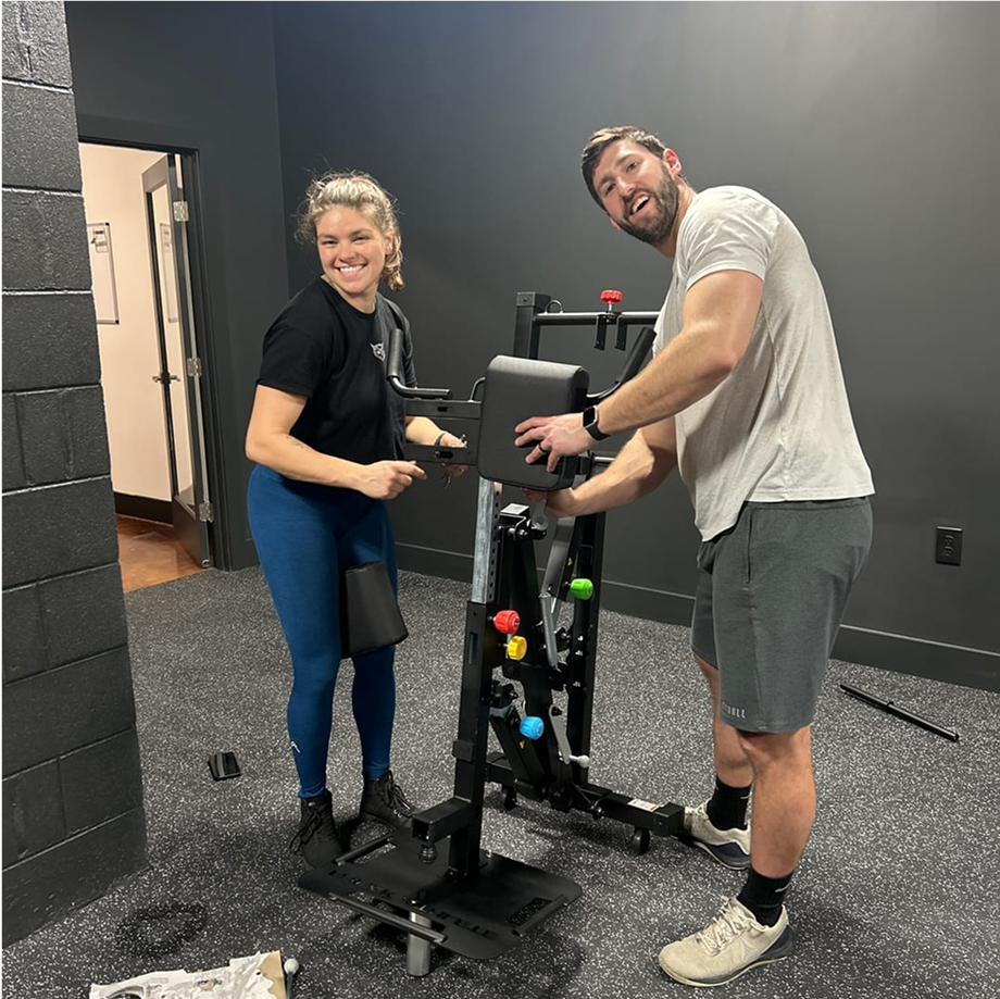 Two people assembling gym equipment in a workout room.