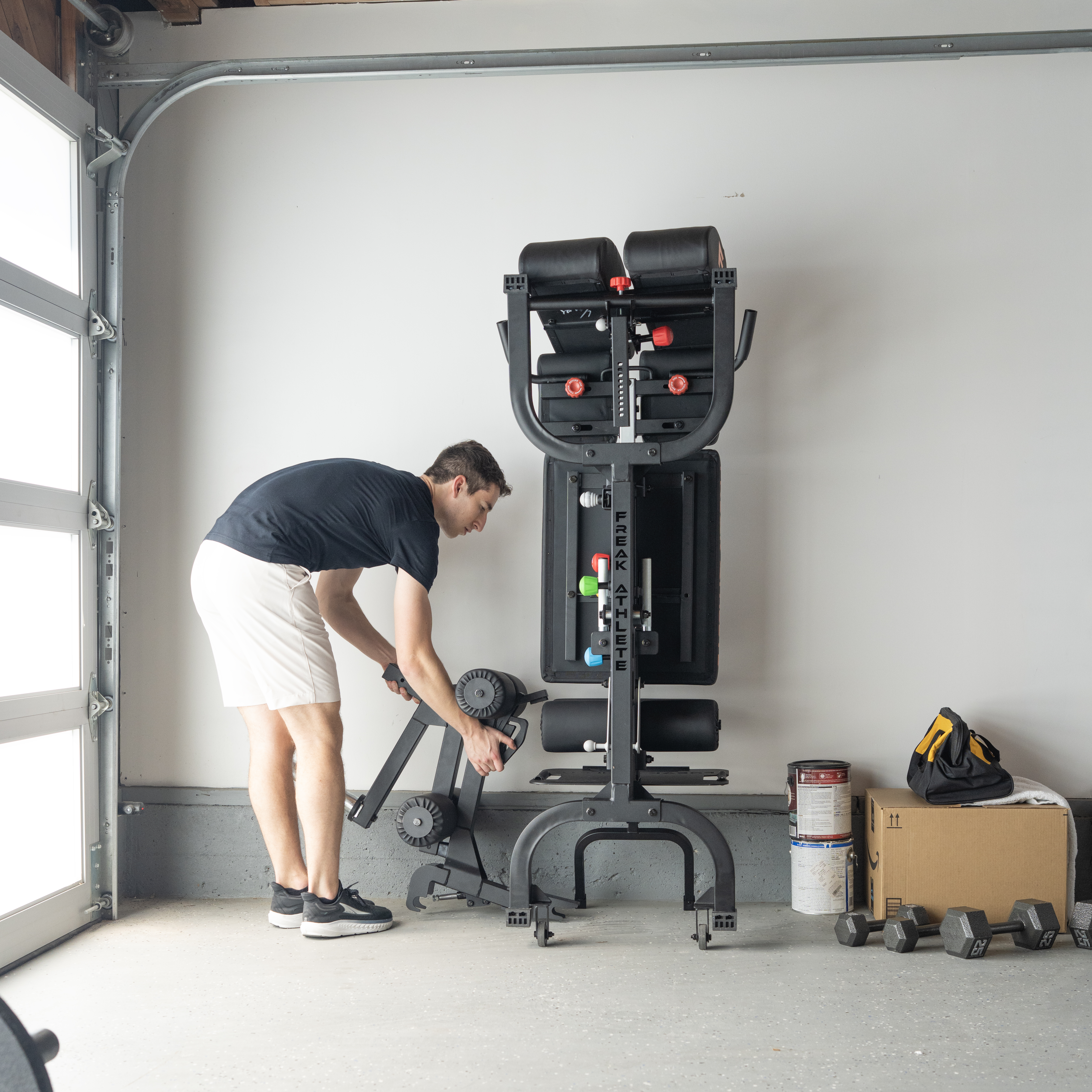 Man setting up exercise equipment in a garage.