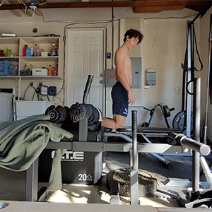 Person exercising on a gym machine in a home garage setting.