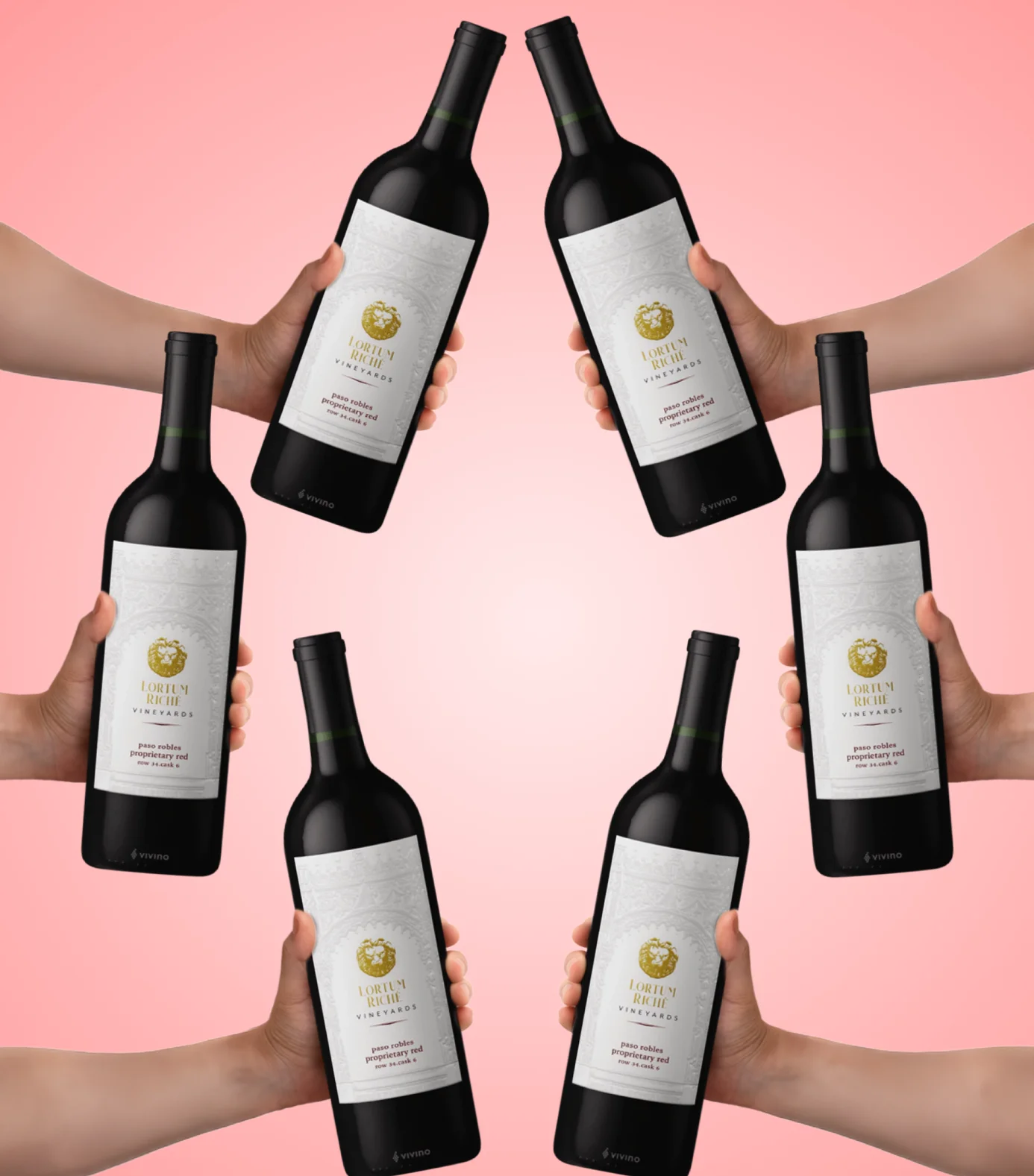 Six hands hold six identical bottles of red wine arranged in a circle against a pink background.