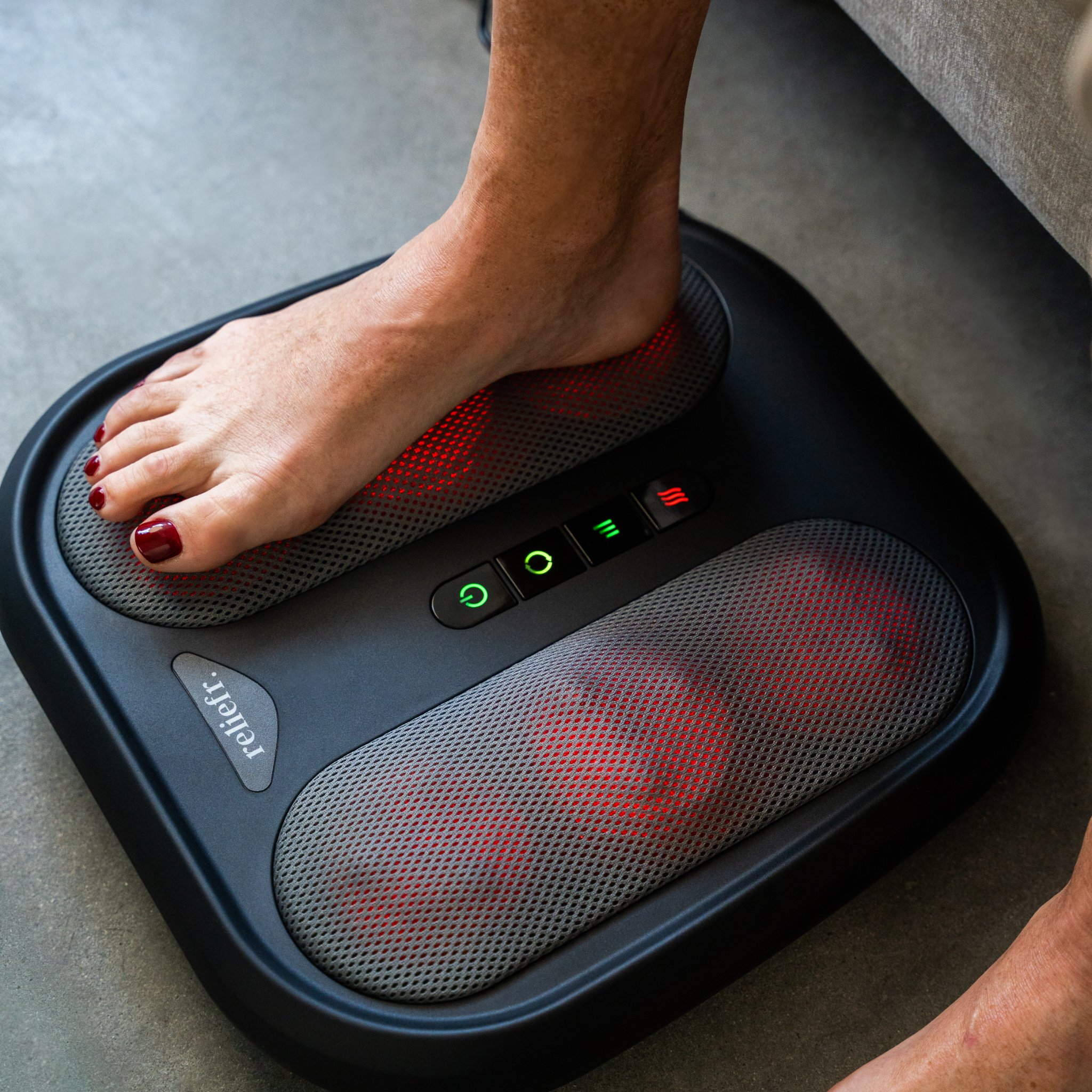 Foot on a red-lit foot massager with control buttons.