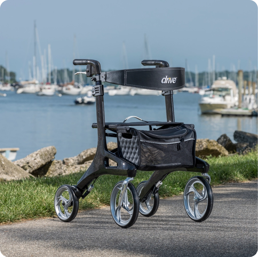 A black walker on a path by water with boats in the background.