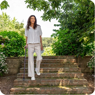 Person walking down brick steps surrounded by lush greenery.
