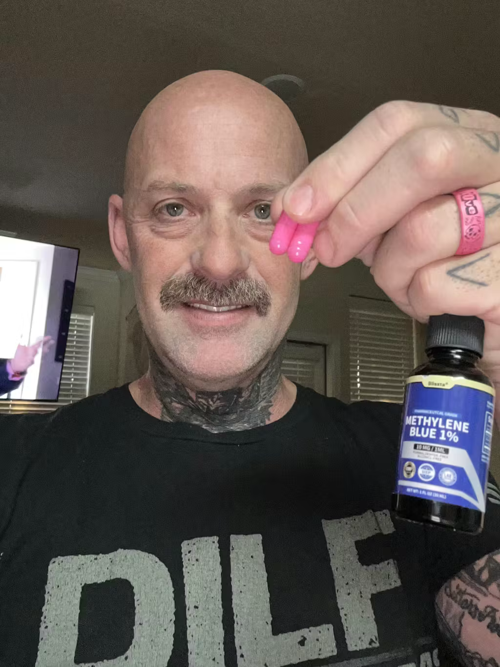 Person holding pink capsules and a bottle labeled 'Methylene Blue 1%'.