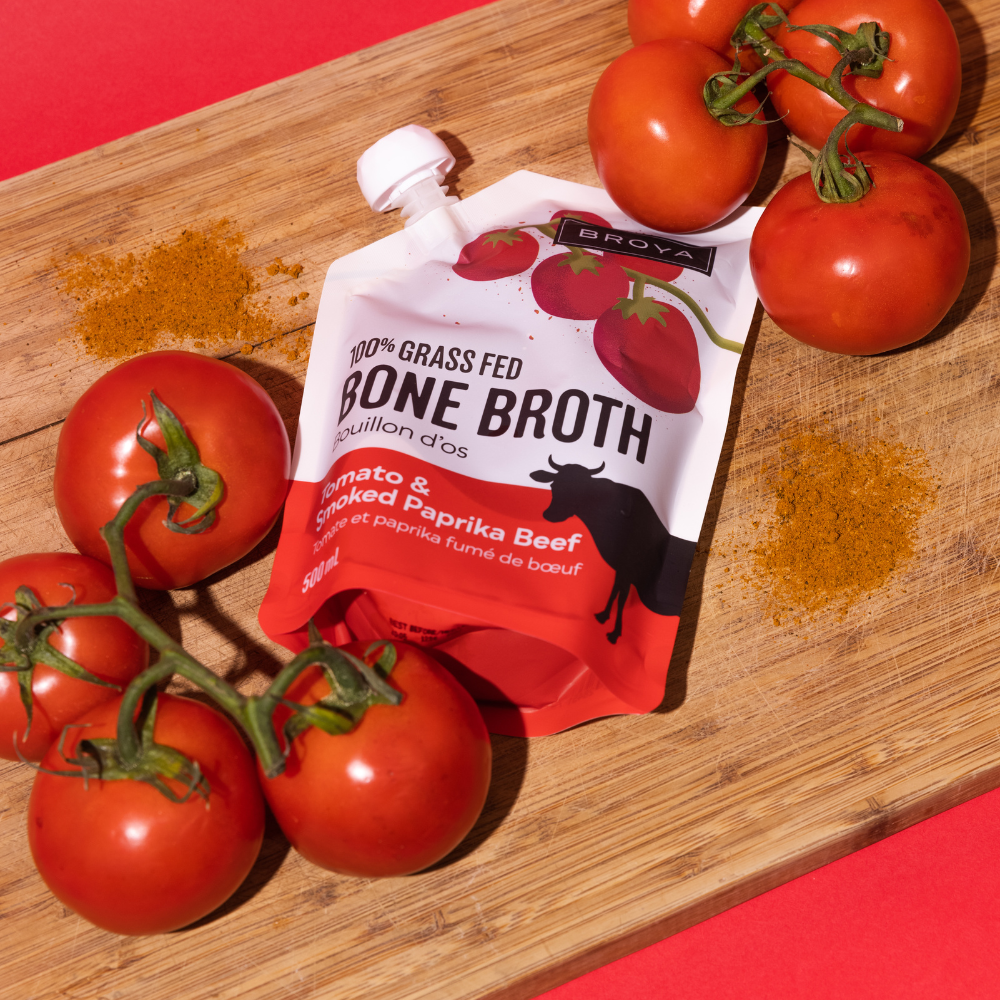 Bone broth pouch with tomatoes and paprika on a wooden board.
