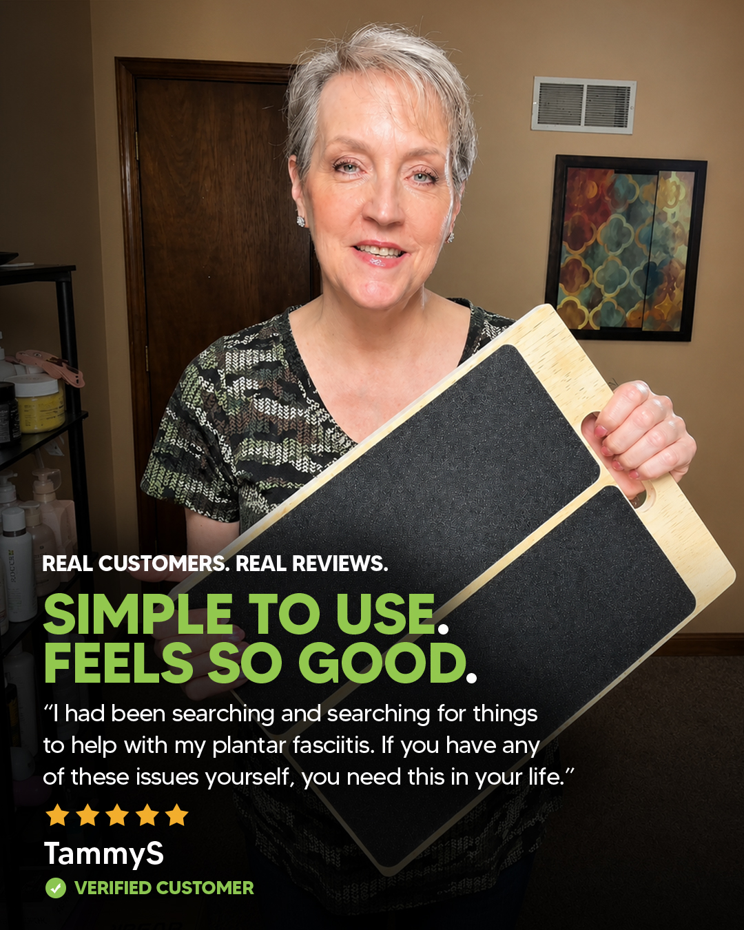 A smiling woman with short gray hair holds a wooden slant board with black non-slip pads.