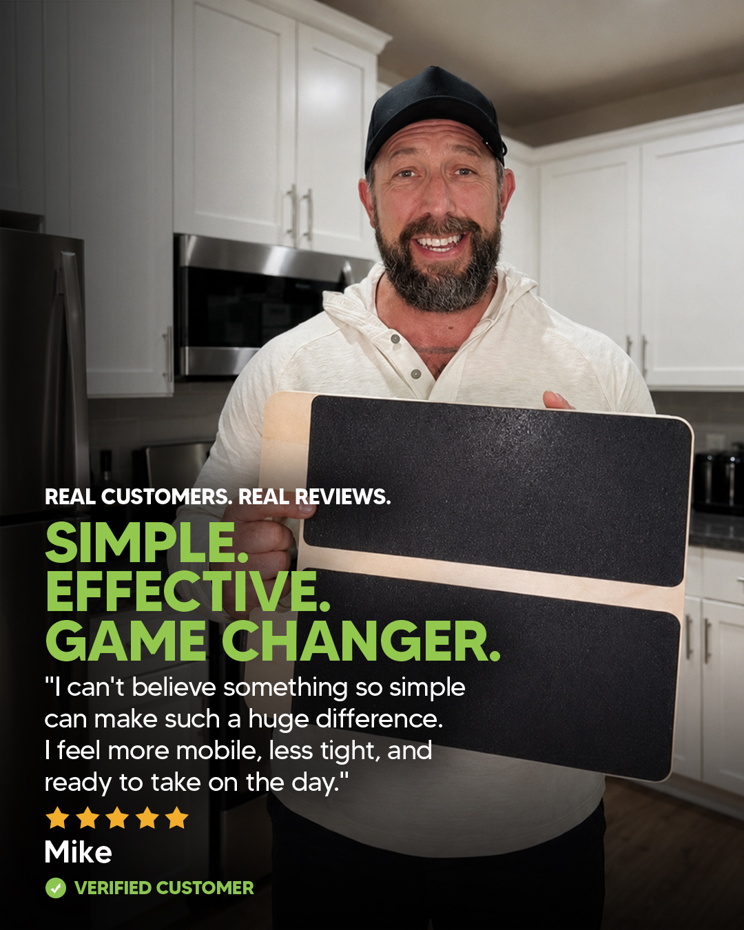 A smiling man in a kitchen holds a wooden board with black grip surfaces and a customer review.