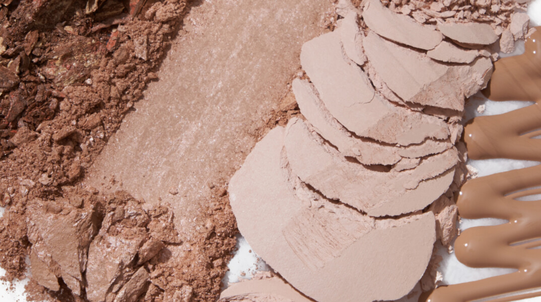Various shades of powdered and creamy makeup products.