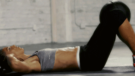 Person doing sit-ups with a medicine ball on their feet.