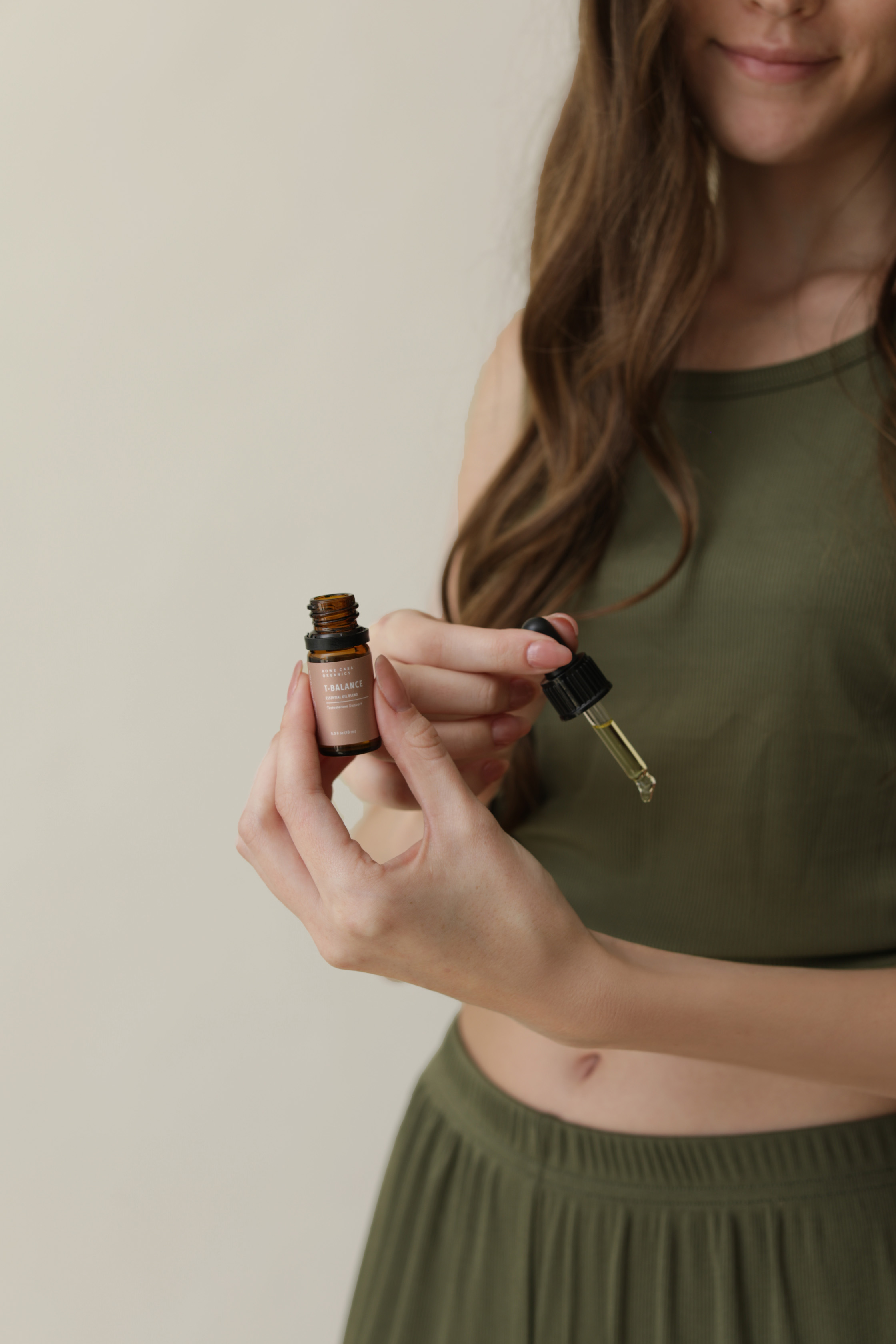Person holding a small bottle and dropper in their hands.