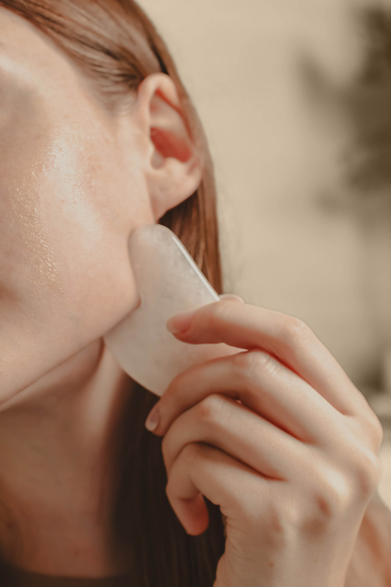 Person using a stone tool on their jawline.