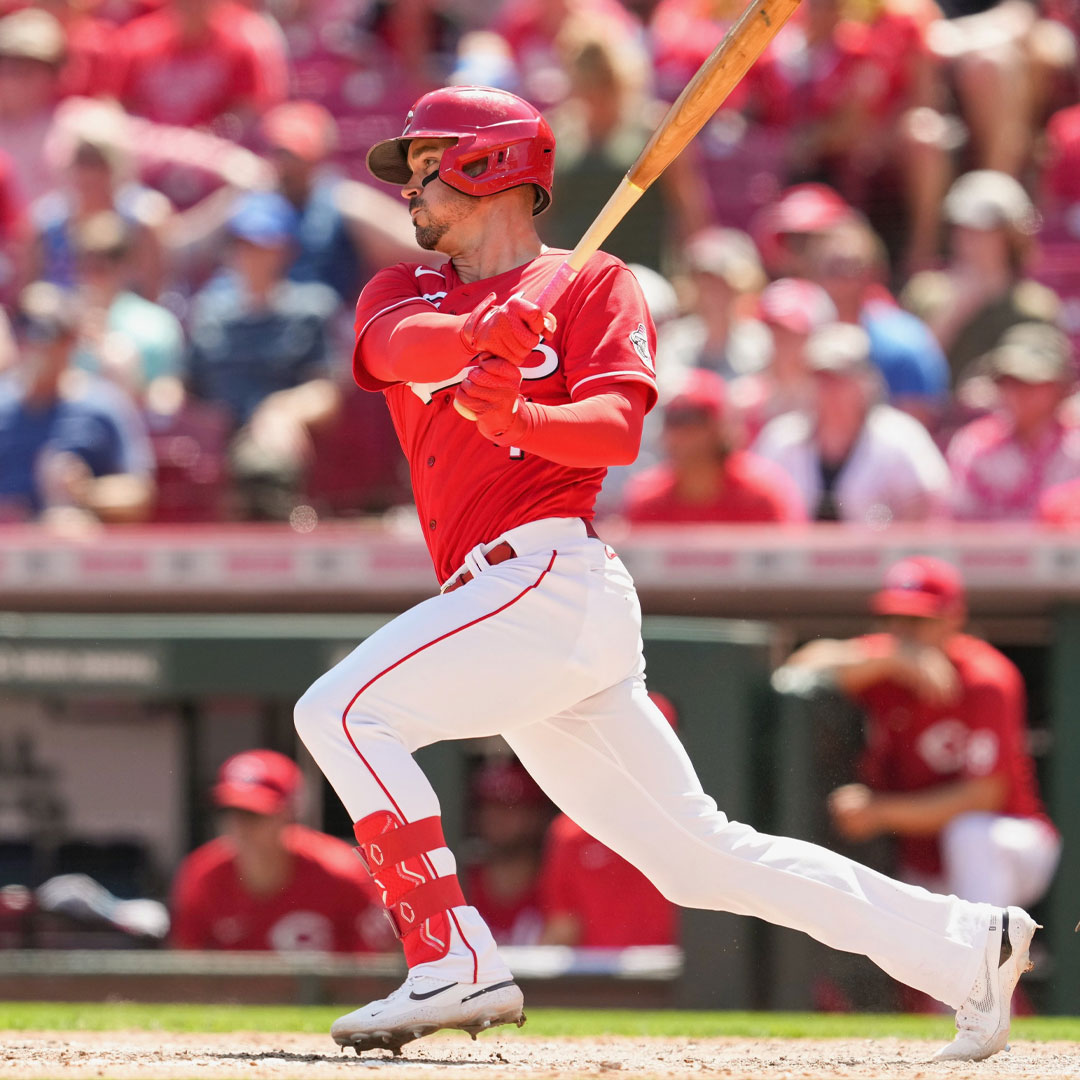 Baseball player in red uniform swinging a bat during a game.