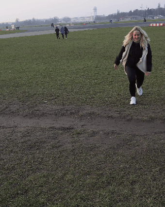 A person running on a grassy field with people in the background.