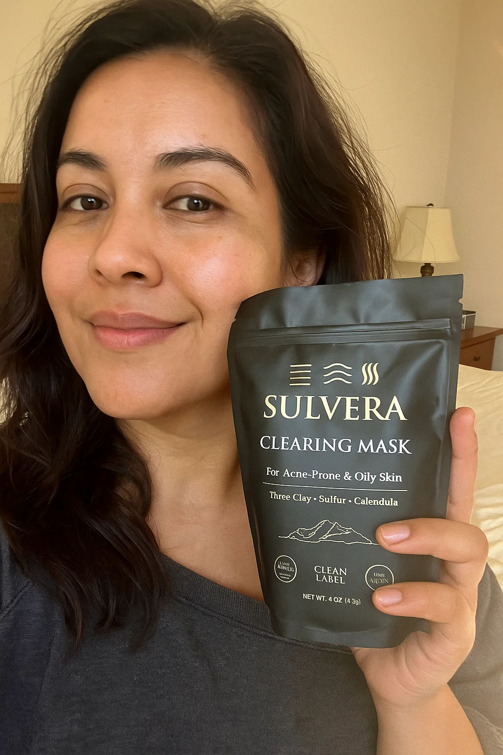 Person holding a Sulvera Clearing Mask package, smiling indoors.