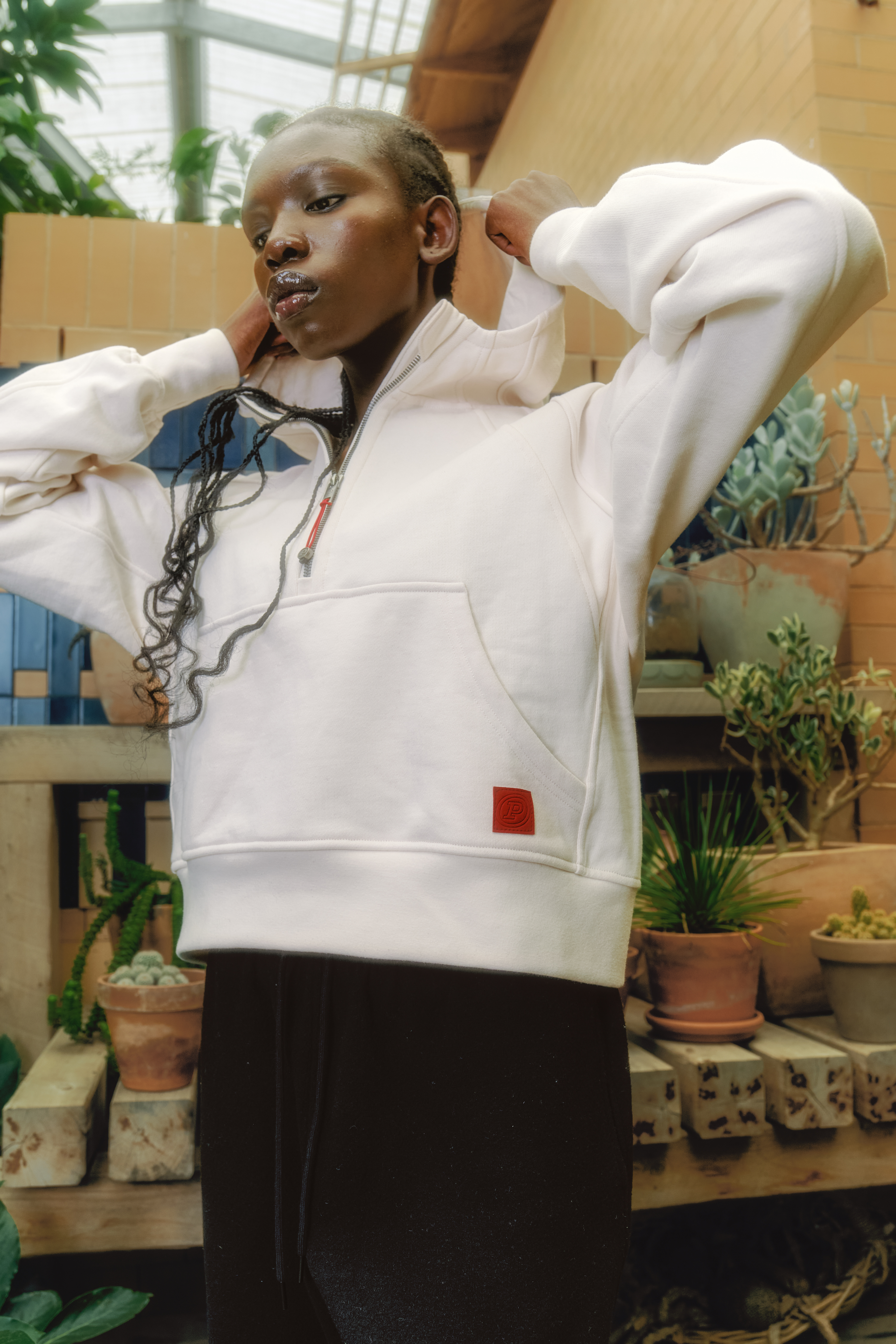 Person wearing a white hoodie with a garden background.
