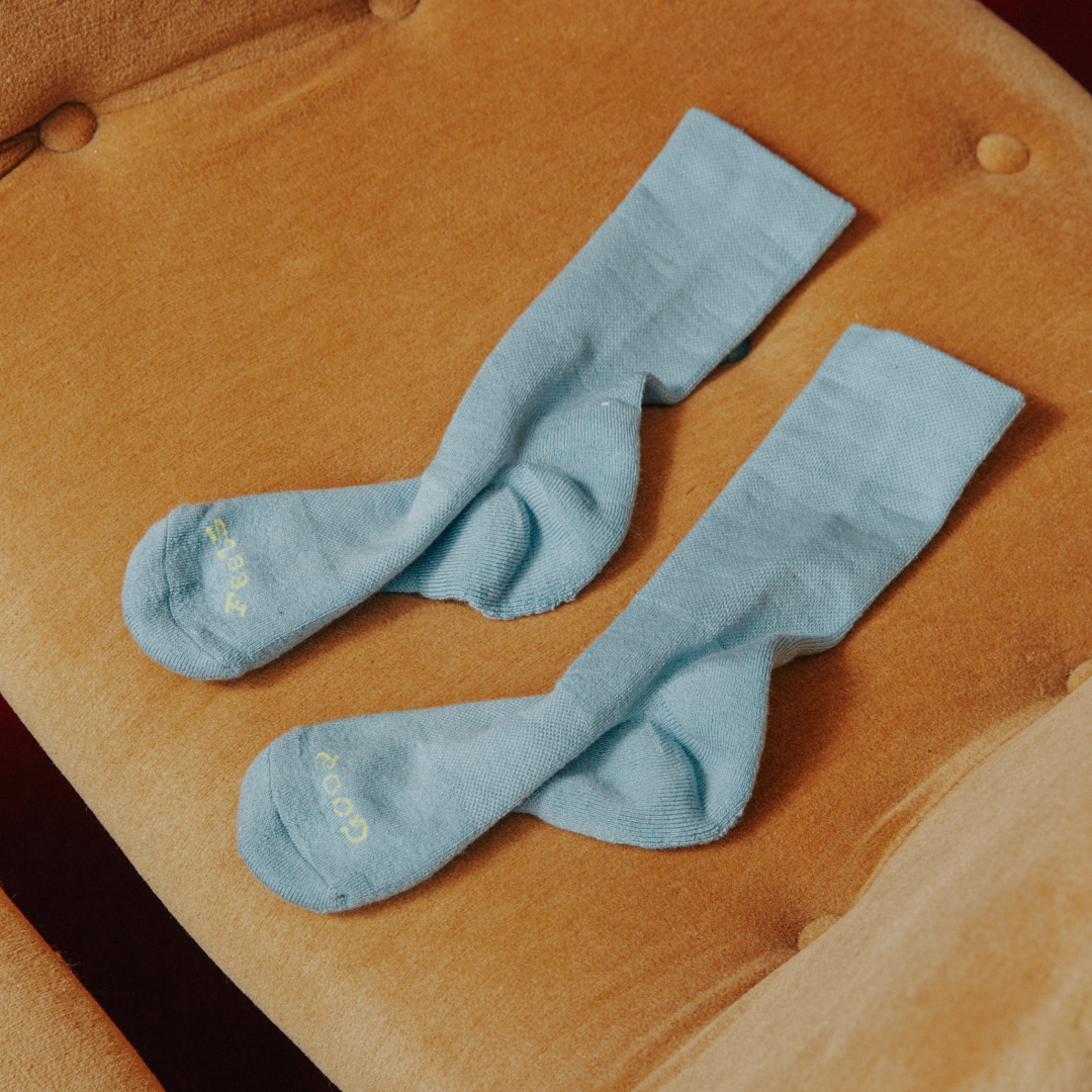 Pair of blue socks on a brown cushioned chair.