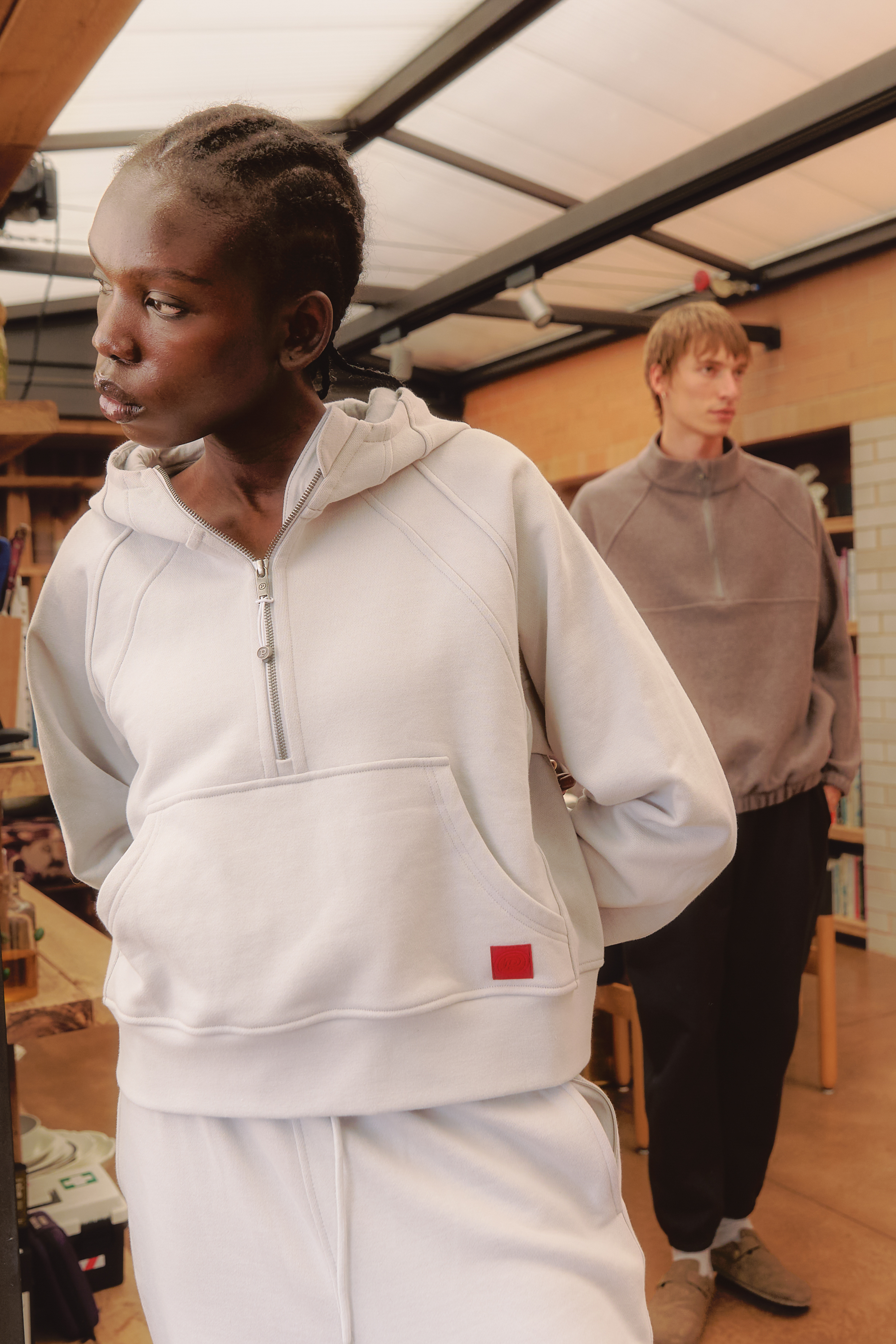 Two people wearing casual hoodies in a cozy indoor setting.