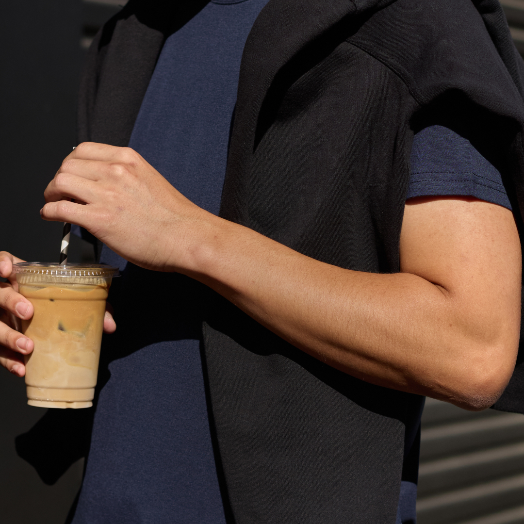Person holding an iced coffee with a striped straw.
