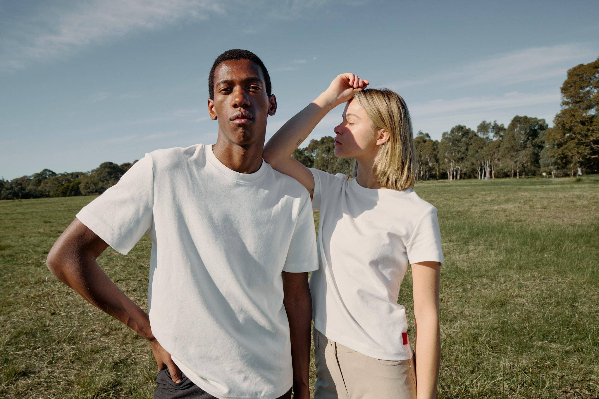 Two people in white shirts standing in a grassy field.